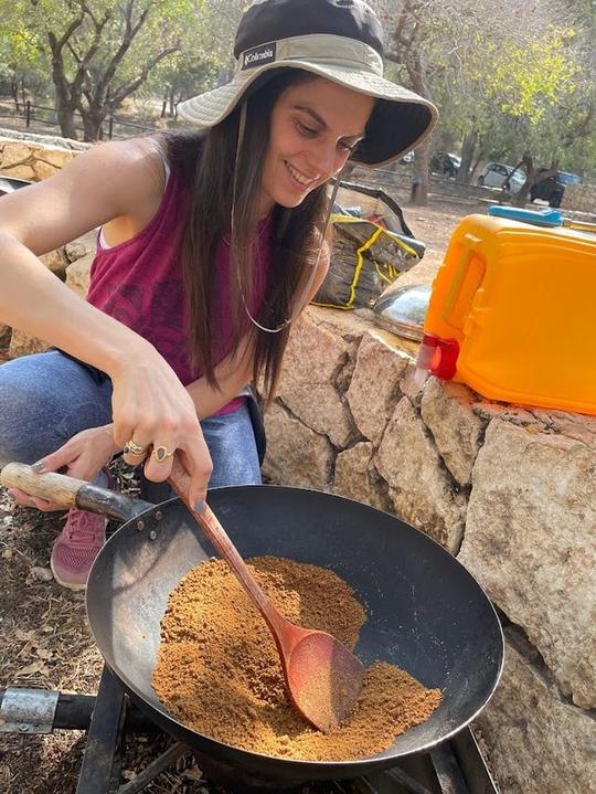 דפנה מבשלת במחבת על אש במחנה